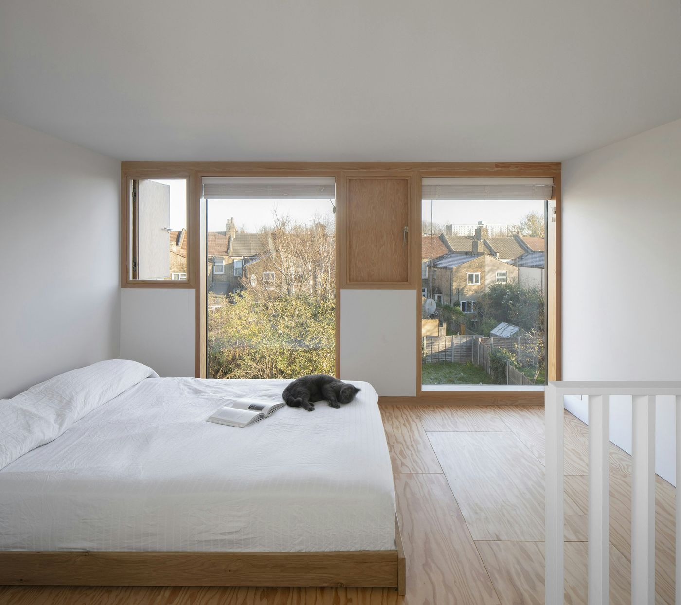 Interior view of the warm douglas fir timber windows in the new master bedroom suite within From Works loft conversion and rear dormer extension in East London.